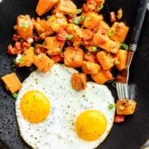 black plate with eggs and hash on it