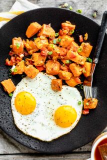 black plate with eggs and hash on it