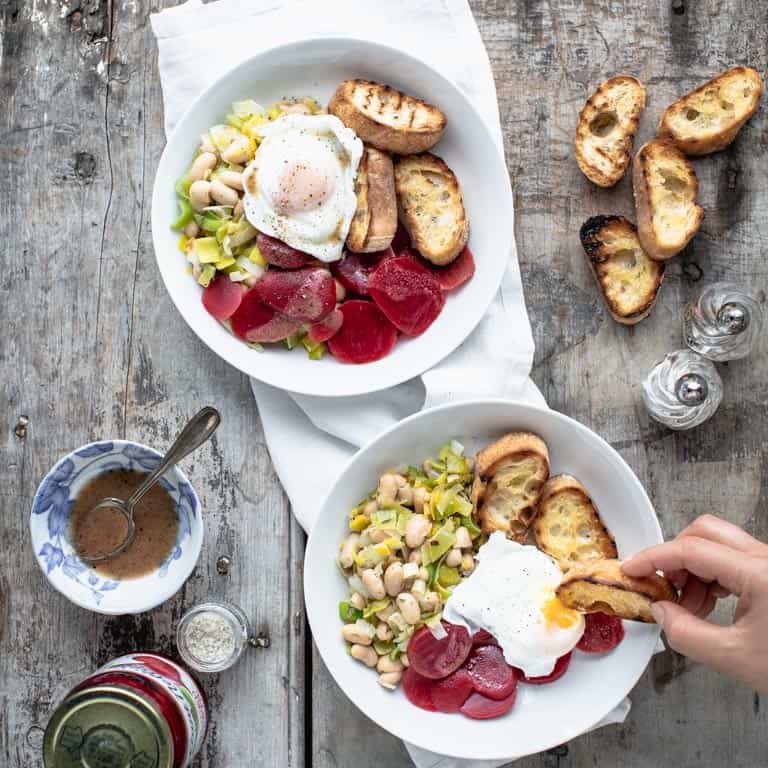 2 bowls of 20 minute pantry Dinner with a hand using a baguette slice to dip into egg yolk