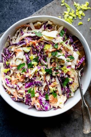 a closeup of the coleslaw with some celery hearts on the table surface