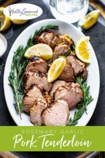 Grilled pork on a platter garnished with rosemary sprigs and lemon wedges
