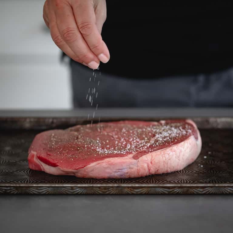 sprinkling salt on steak