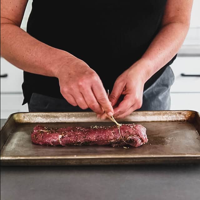 Fold the tail (thin) end of the pork tenderloin under and secure it with butcher twine