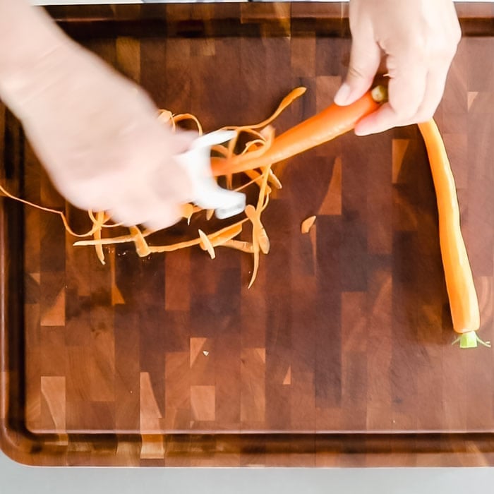 Remove carrot greens and peel them.