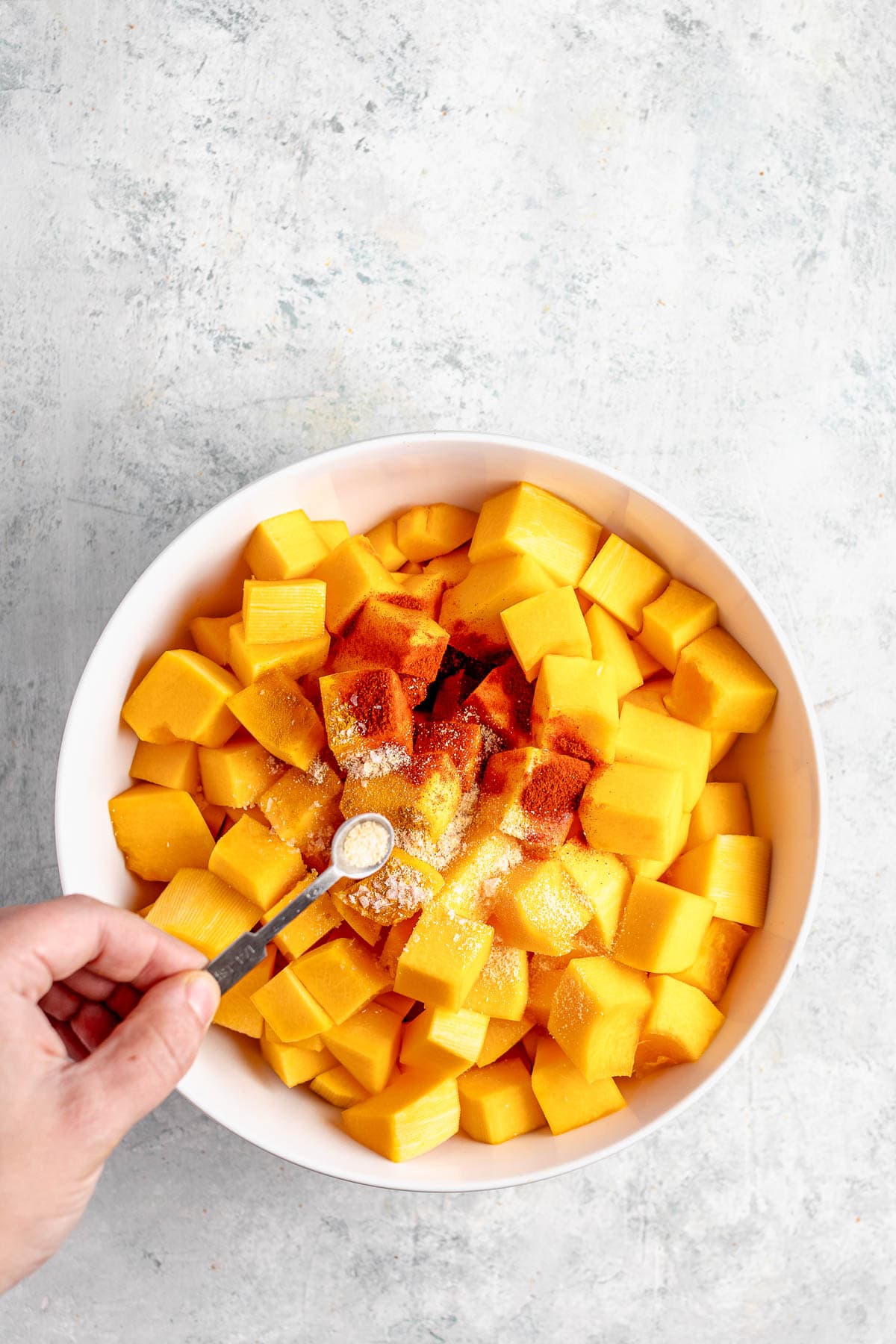 adding the spices to the cubed butternut squash