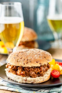 a sloppy joe sandwich on a bun on a black plate