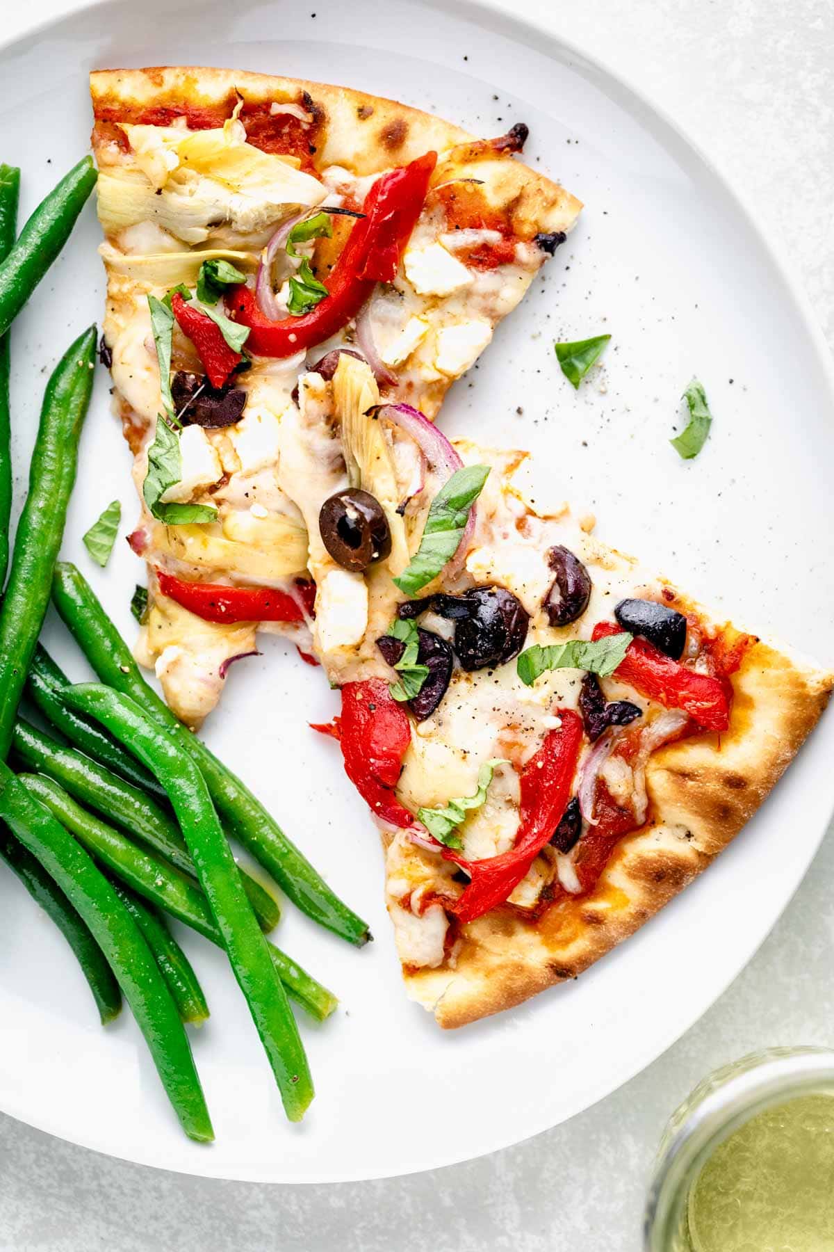 Greek Pizza slices on a plate with green beans