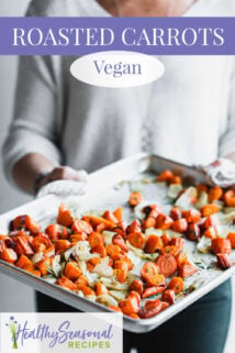 holding sheet pan of roasted carrots