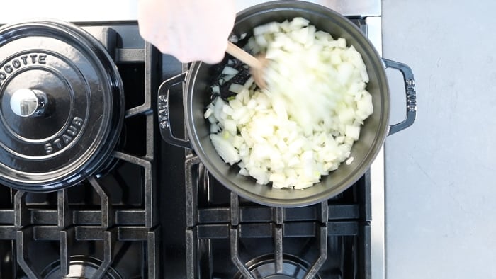 cooking the onion in a Dutch oven with a wooden spoon