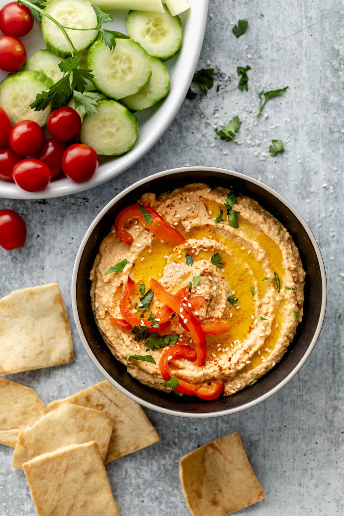 the hummus in a bowl with chips scattered on the table a platter of veggies is near by