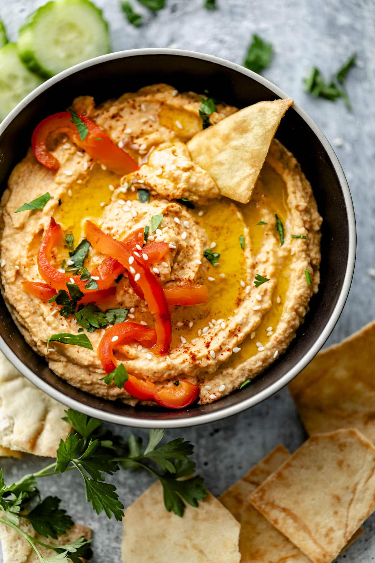 the hummus with a chip in it, drizzled with oil and roasted peppers on top