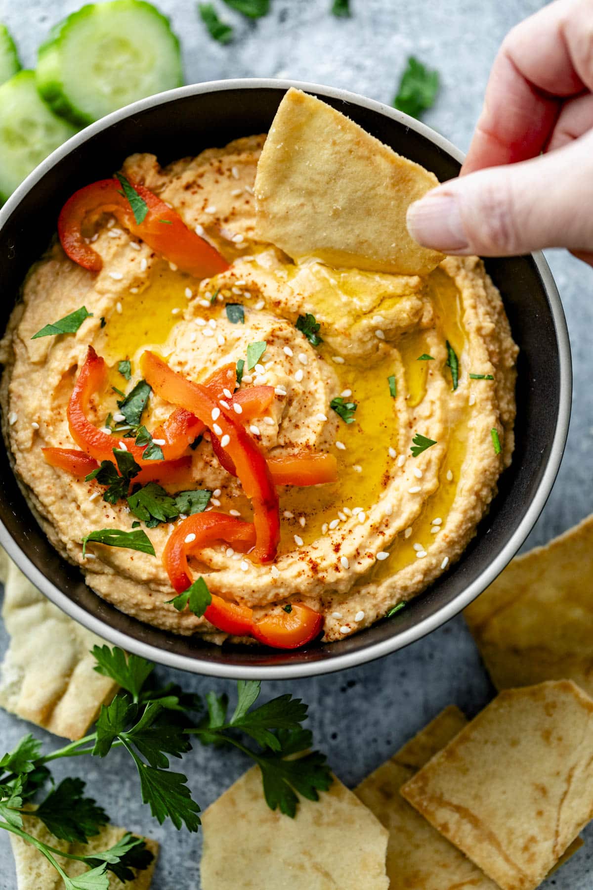 the hummus in a black bowl with a pita chip getting dunked into it