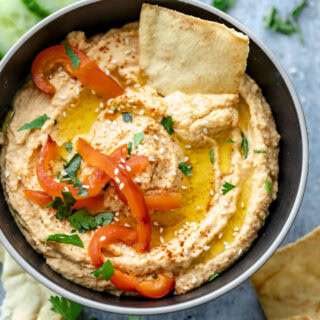 the hummus with a chip in it, drizzled with oil and roasted peppers on top