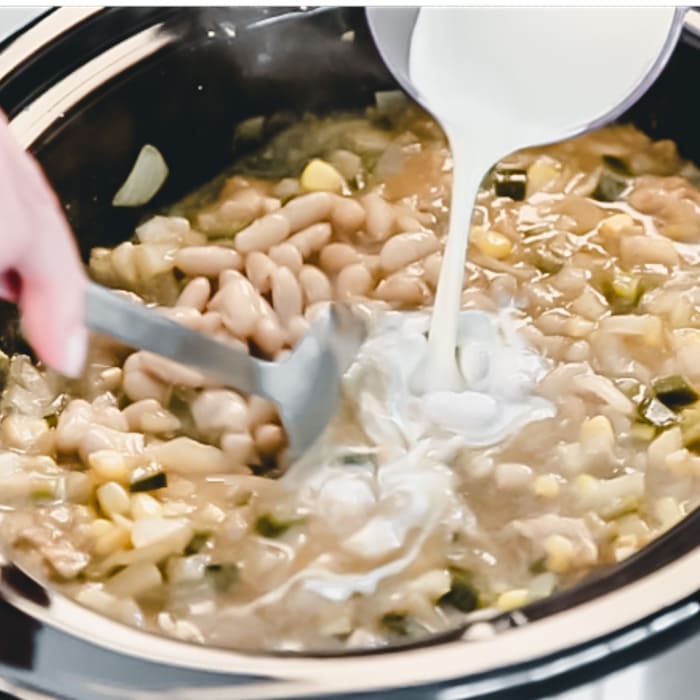 pouring heavy cream into white chili