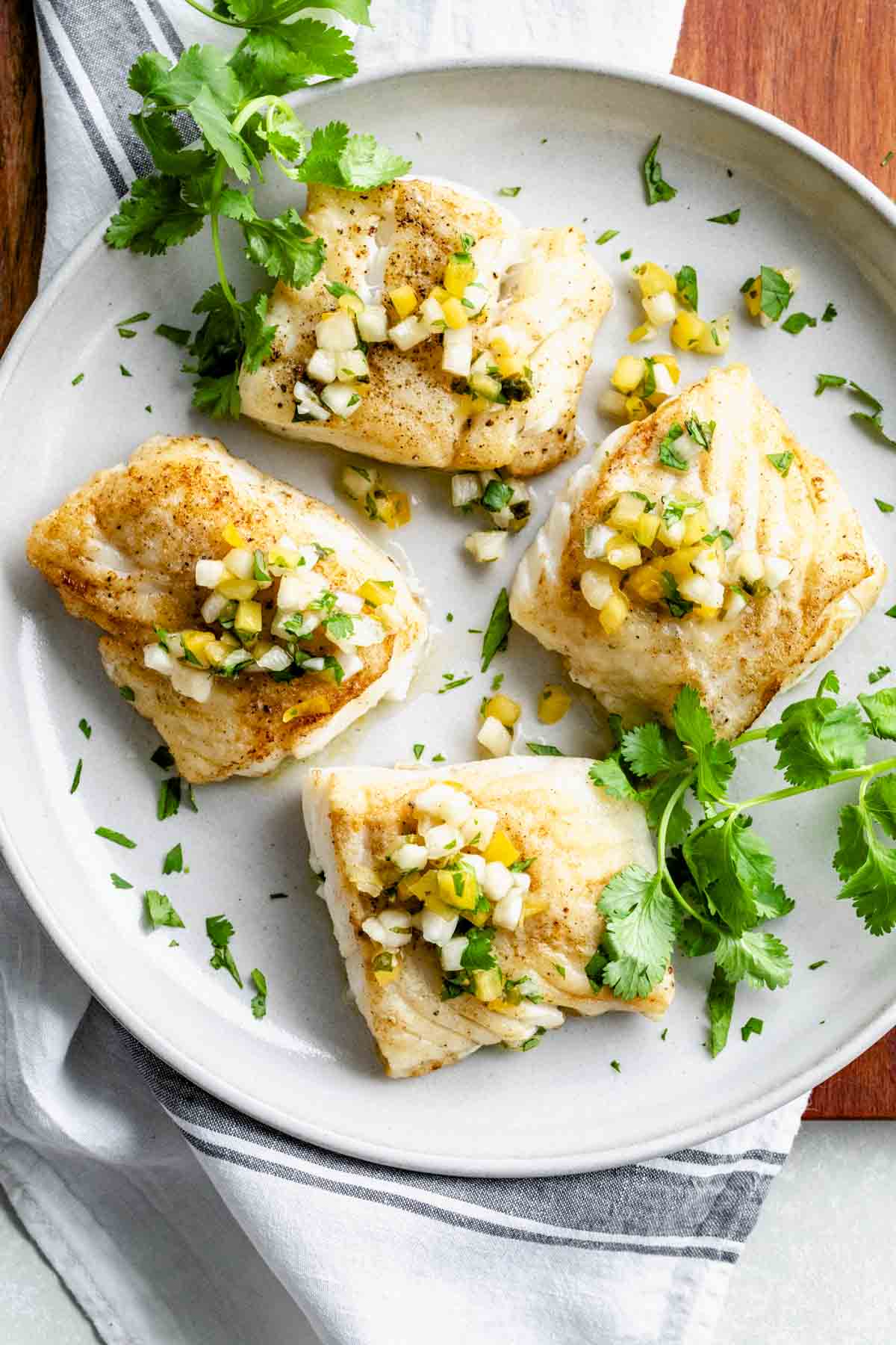 four filets of cod with pineapple salsa and cilantro sprigs
