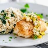 golden browned cod filet with pineapple salsa and rice on a white plate from a side angle
