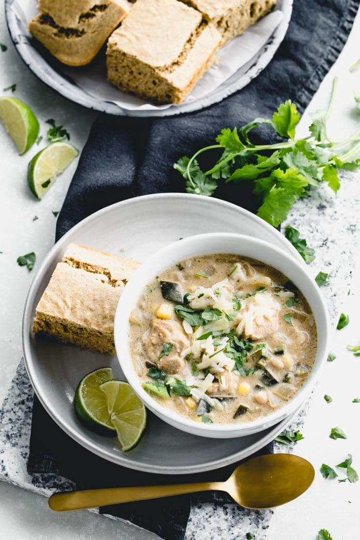 An overhead table scape with white chicken chili and cornbread