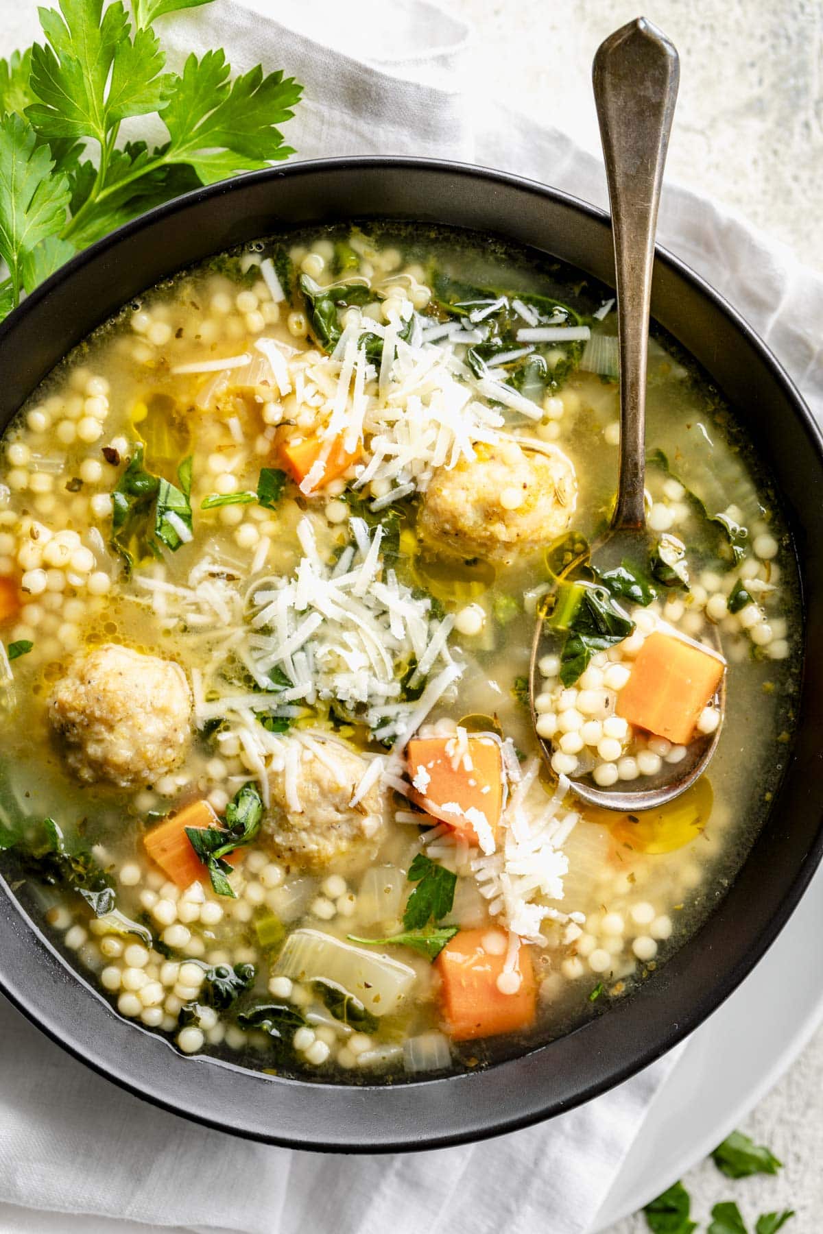 a close up look at the soup from overhead looking into the bowl chunks of carrots and the chicken meatballs are clearly visible. A layer of Parm is sprinkled on top