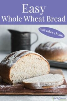 Loaf of whole wheat bread cut on wood cutting board and one uncut loaf of bread