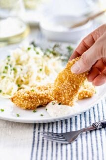dipping fish sticks into tartar sauce