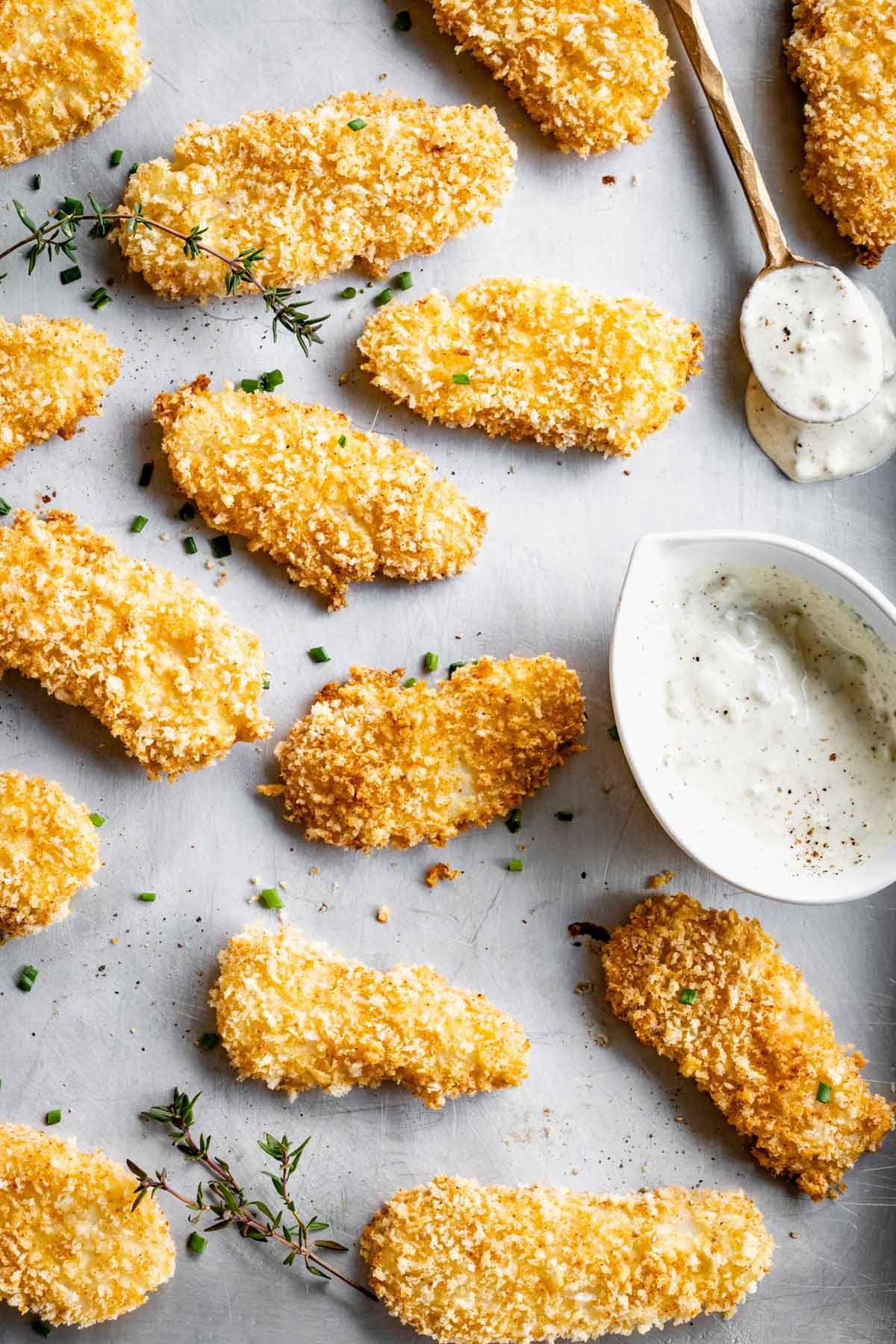 sheet pan with the baked fish sticks an a ramequin of tartar on it