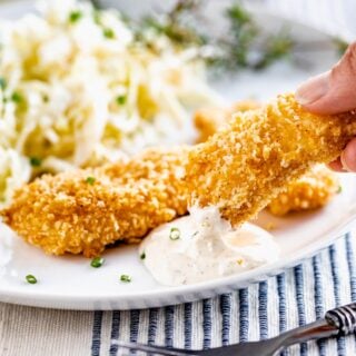 close up of dipping fish sticks into tartar