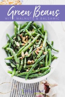 three quarter view of bowl with green beans topped with balsamic and walnuts