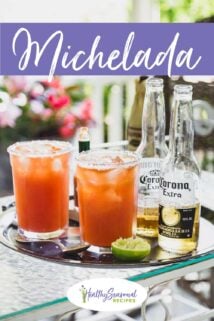 two micheladas on a tray with two half bottles of beer and lime on it too