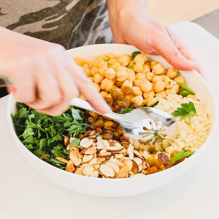 8. Add the couscous to the dressing and stir to combine. Add in the chickpeas, parsely, almonds and raisins and stir again.