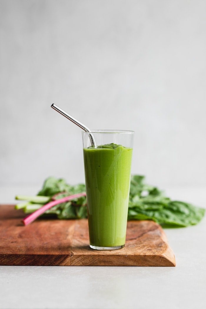 Green smoothie on a wood cutting board with with Swiss chard.