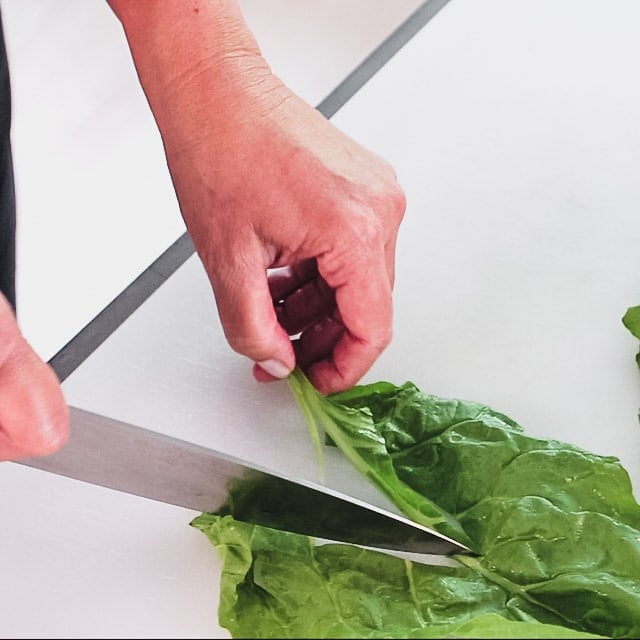 Using a knife to remove stems from chard leaf