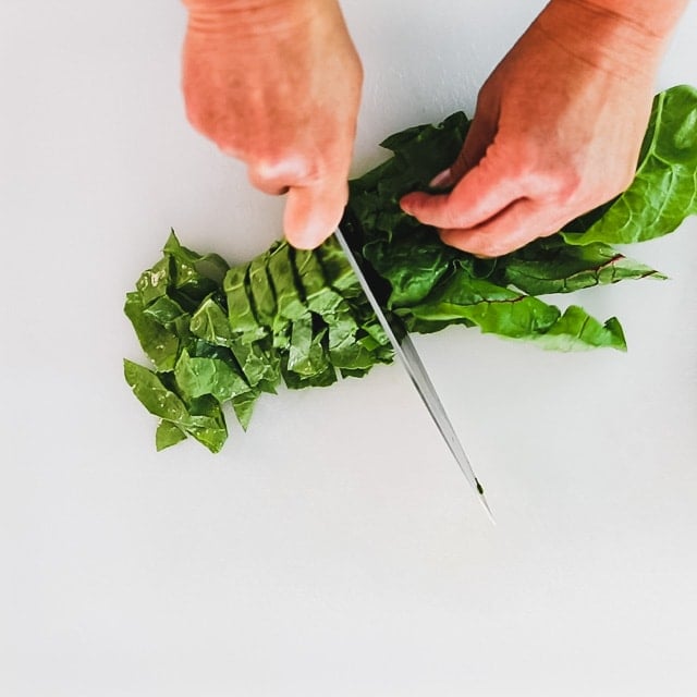 Using a knife to chop chard leaves