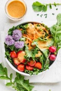 Thai dressing over a salad with chive blossoms