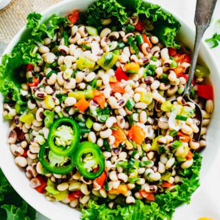 a closeup of texas caviar in a bowl garnished with lettuce and jalapeno rings