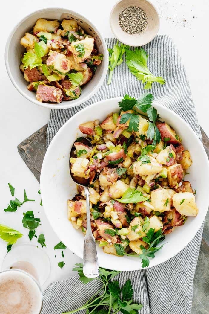 German potato salad in a serving bowl plus a single serving