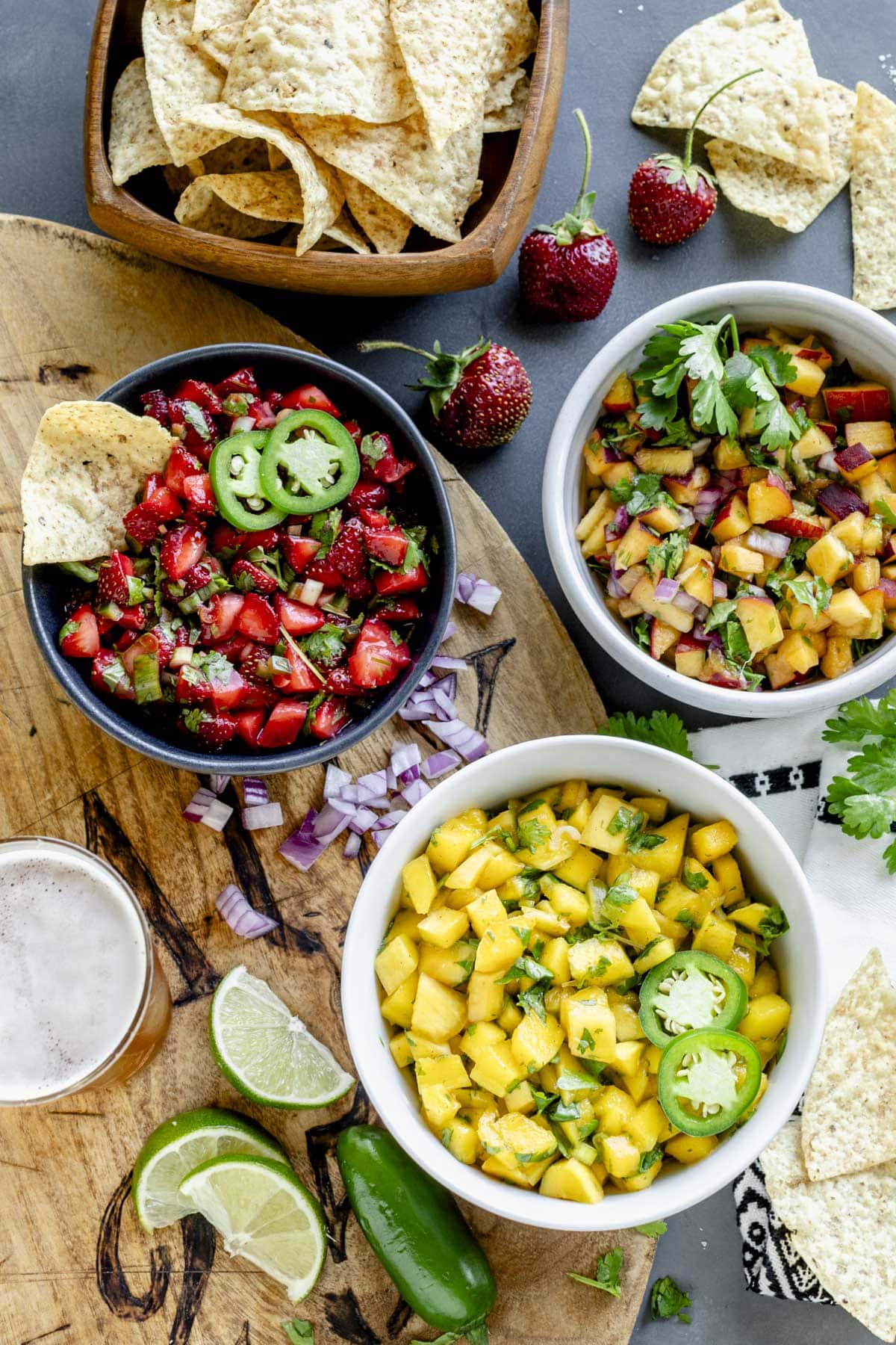 three bowls of salsa with chips and lime