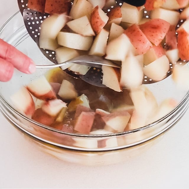 adding the potatoes to the dressing