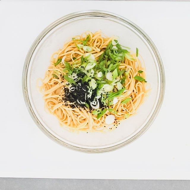 The noodles, scallions and sesame seeds added to the bowl of dressing