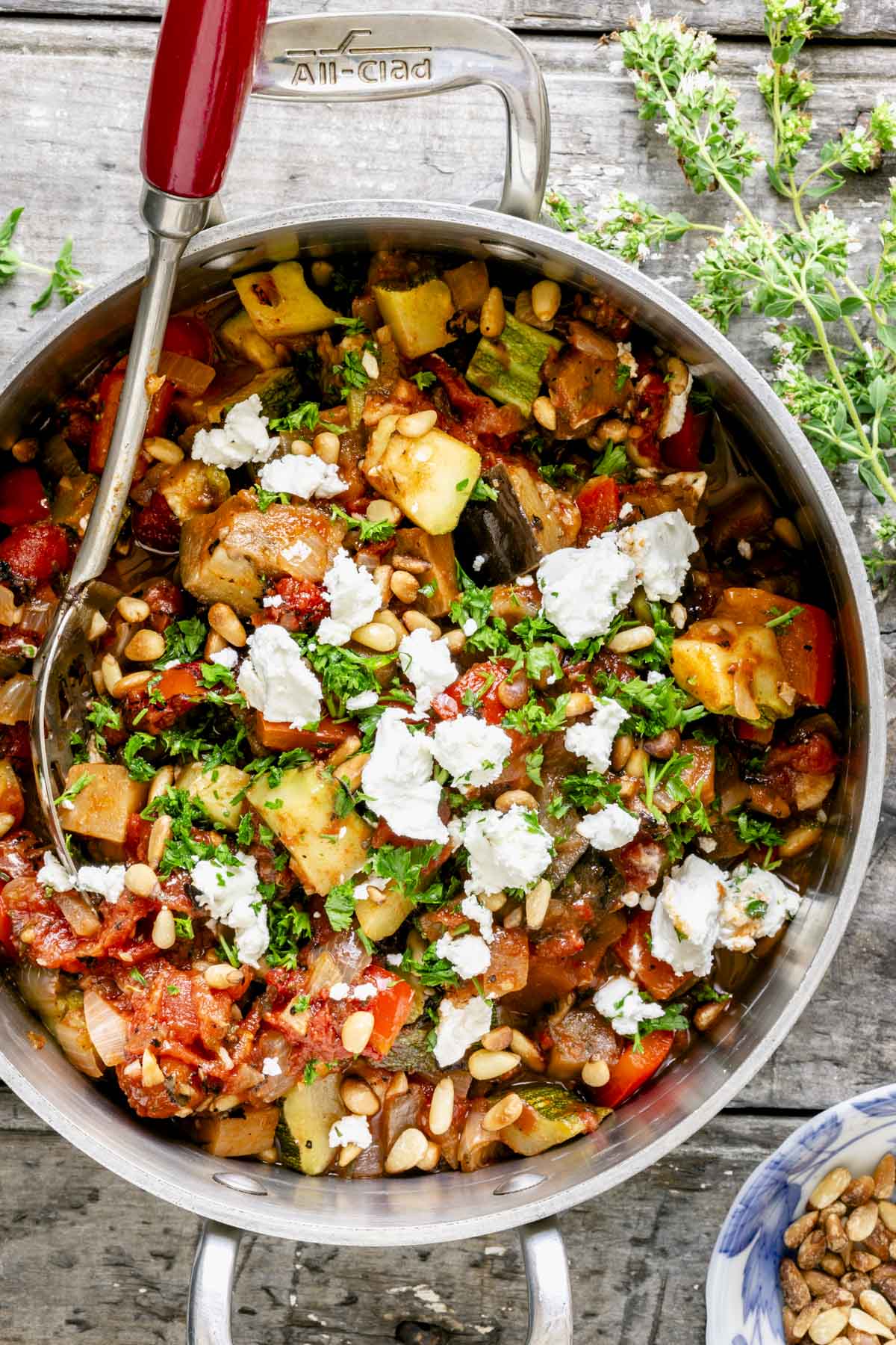 ratatouille stew in a dutch oven with an old fashioned spoon with a red wooden handle