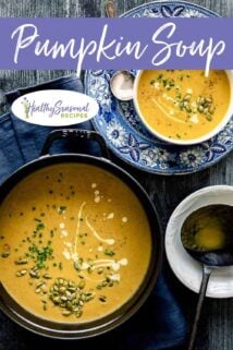 pumpkin soup in a bowl on a blue and white plate with a black pot of soup