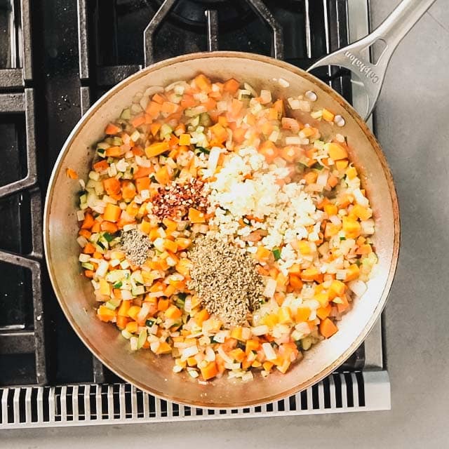 Spices and garlic added to large skillet with carrots, onions and zucchini