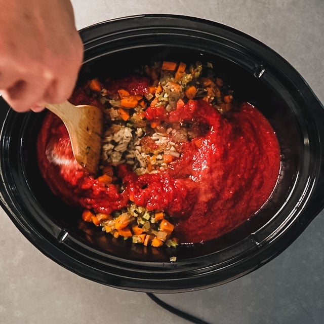 Adding tomatoes and sugar to a slow cooker with turkey and vegetables
