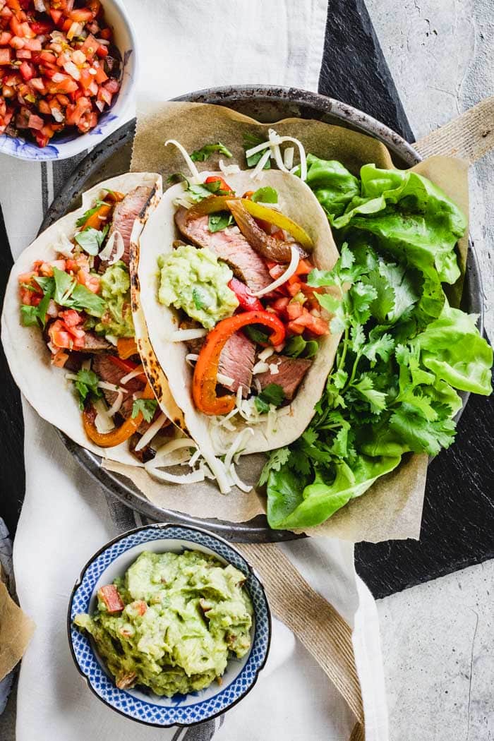 Easy Steak Fajitas in tortillas on a plate with lettuces and cilantro