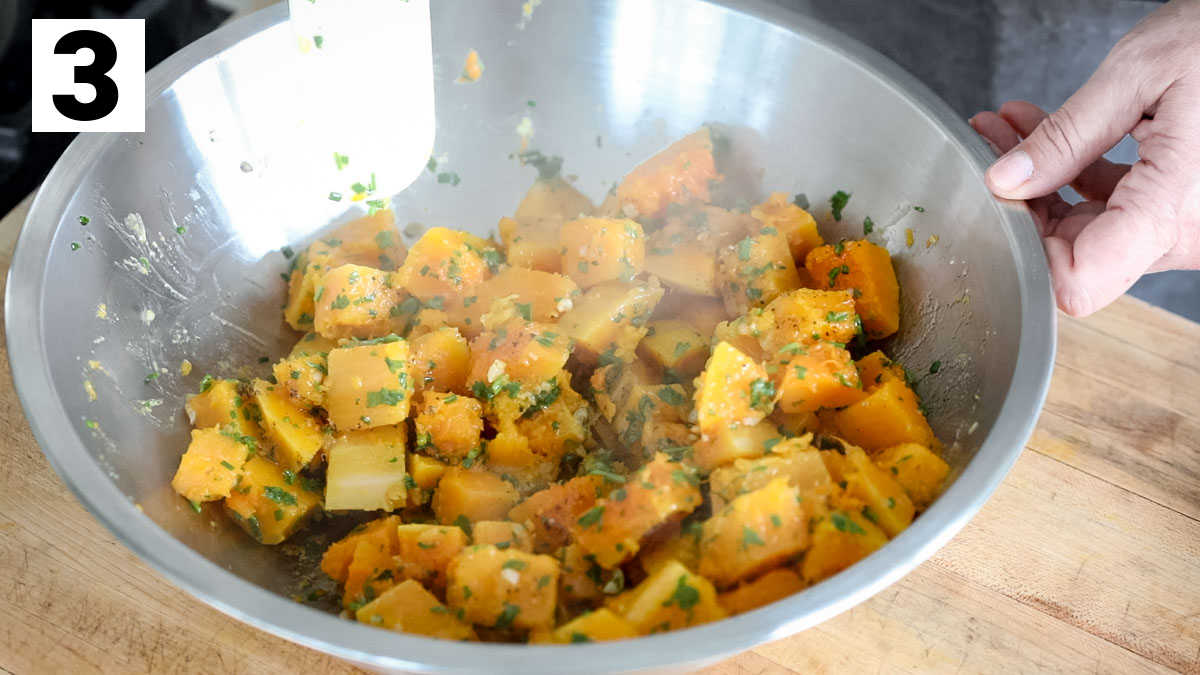 mixing the steamed squash with the herbs and garlic in a metal bowl