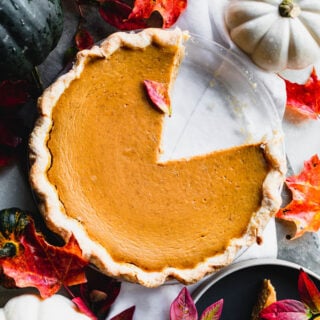 closeup of the pie overhead with a slice removed. Fall leaves around it