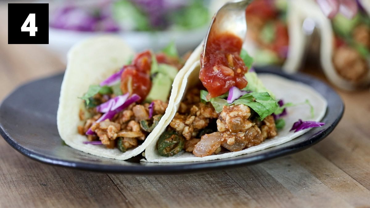 adding the toppings to the chicken tacos
