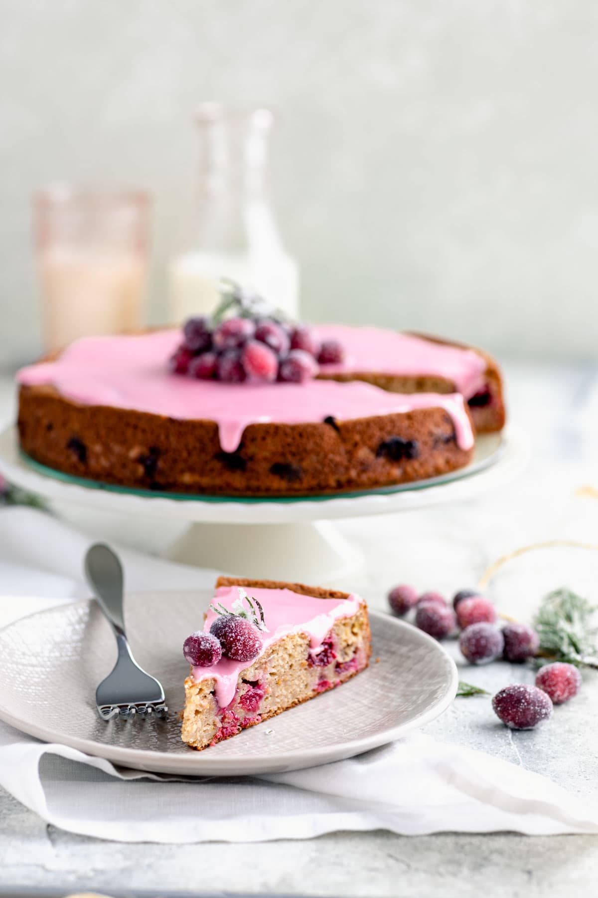 cranberry cake slice on a plate in front of the cake stand