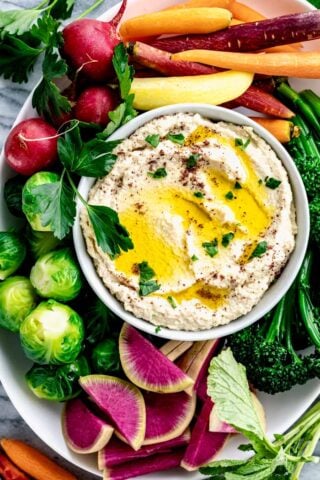 a platter of veggies with a bowl of hummus in the center