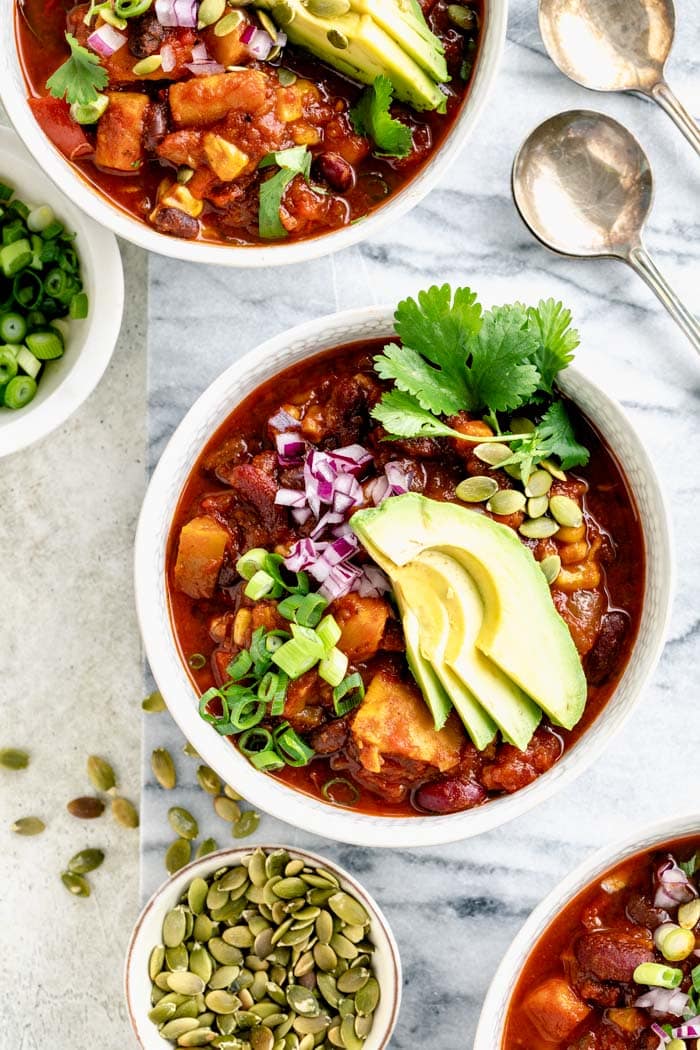 bowls of chili from overhead with avocado fans and cilantro sprigs