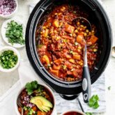 Slow Cooker chili in the slow cooker with bowls of chili on the table